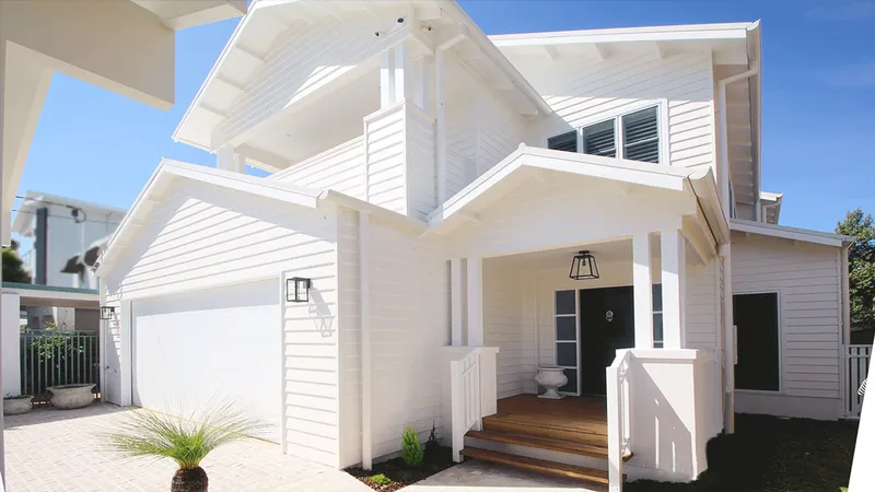 Hampton's style home facade with elevated entrance, white weatherboards, and timber detailing under the eaves.