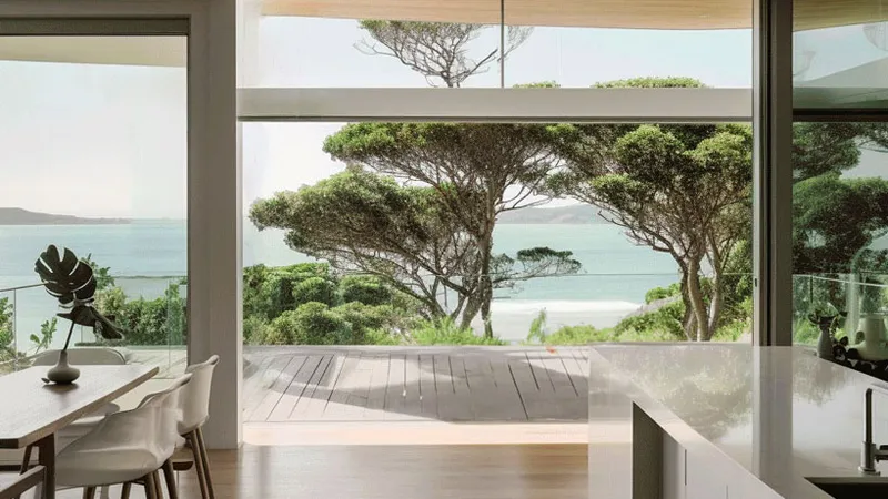 Open plan kitchen and dining room in a modern house with wooden features, designed in an Australian landscape style. The room overlooks dramatic oceanic seascapes.