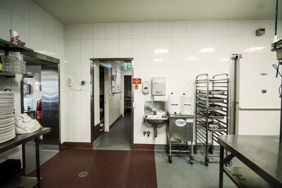 State-of-the-art open commercial kitchen, with zones for cooking and plating, compliant with food and health codes, aiming for efficient large-scale catering.