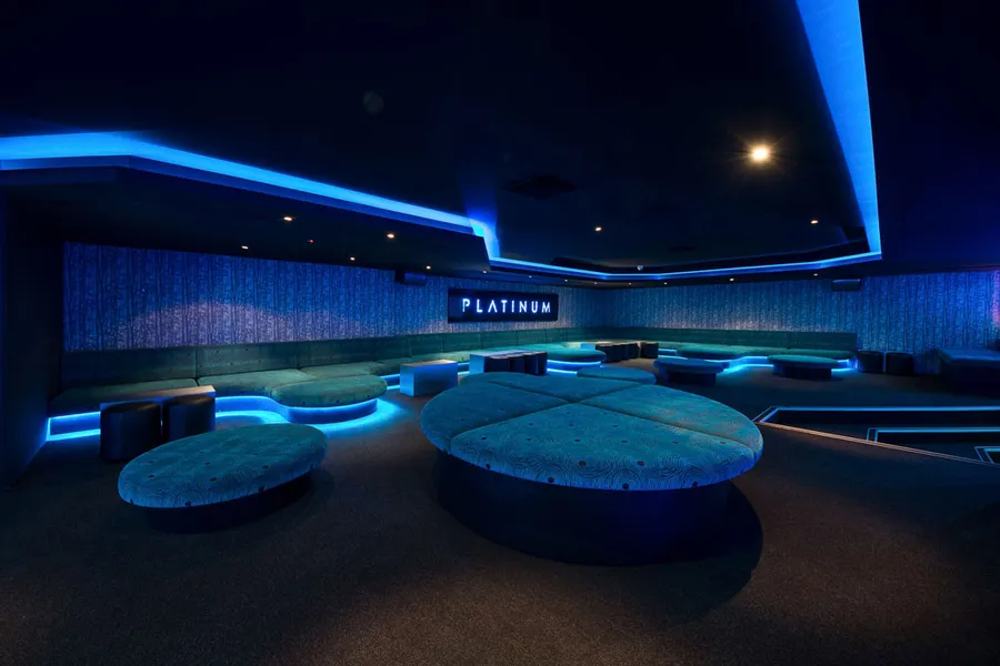 Lounge area overlooking the dance floor in blue-lit nightclub.