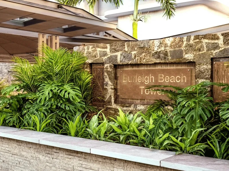 The entry sign to the Burleigh Beach Resort with a lush walkway leading into the main building