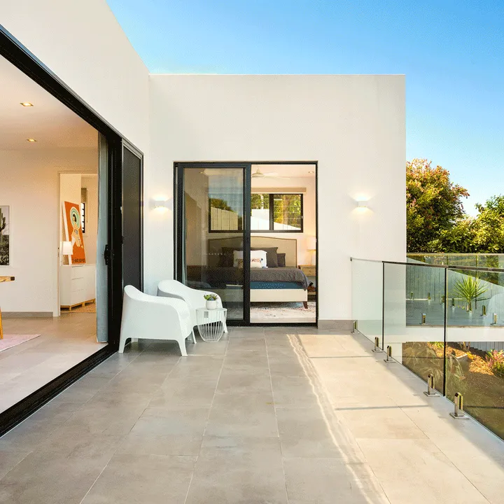 A modern luxury villa with a glass-tiled balcony overlooking a rocky hillside