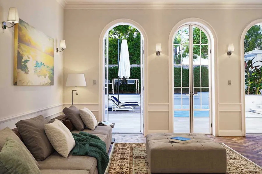 View from the classical living room through arched French doors showcasing an exterior pool area.