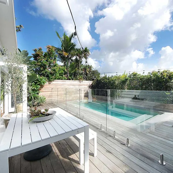 Inviting swimming pool area with surrounding grey-tinted timber decking, enhancing the coastal context of the location