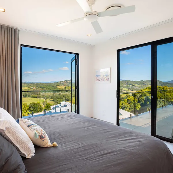 Spacious bedroom featuring glass sliding doors that open onto a balcony, offering stunning views of the outdoors from the comfort of the room