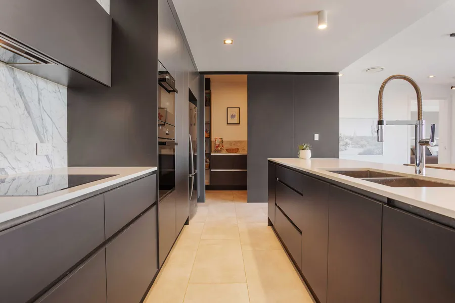 Modern kitchen with flat black handleless cabinetry, marble splashback and concealed butler's pantry