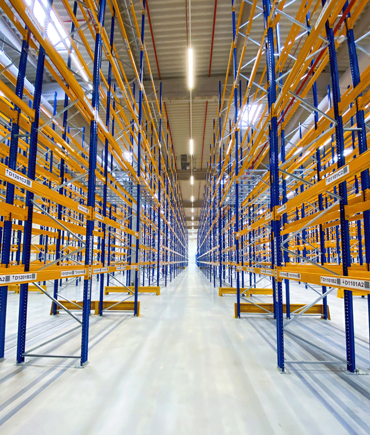 An expansive warehouse building filled with storage racks, exemplifying industrial design aesthetics and technological integration. The space is balanced and clean-lined, bathed in blue and amber hues.