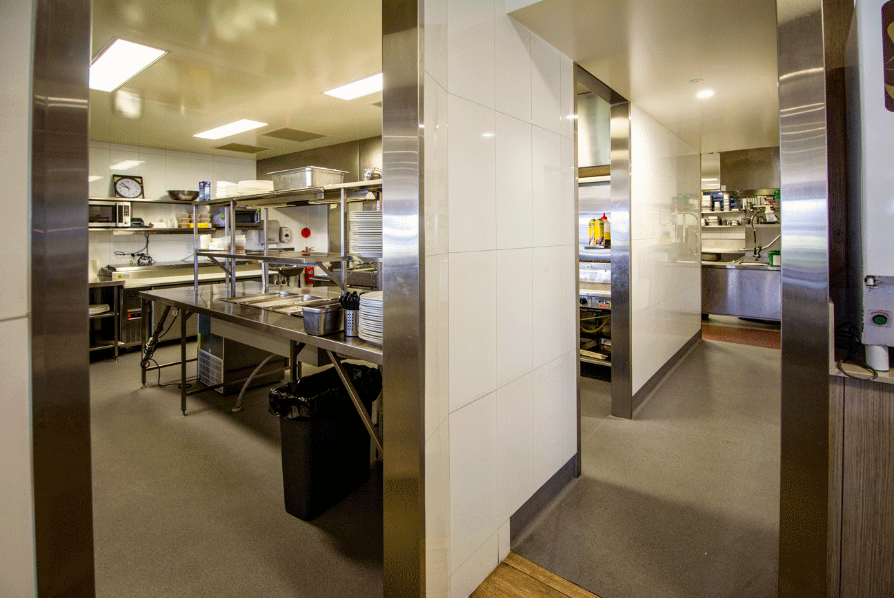 An inviting view into a stainless steel commercial kitchen, showcasing the front of house operation.