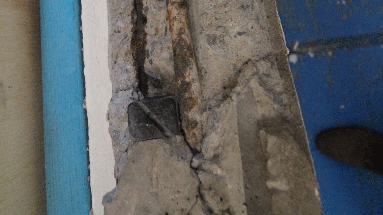 Image showing the deterioration of a building's structural elements due to rusting and corrosion of steel reinforcement.
