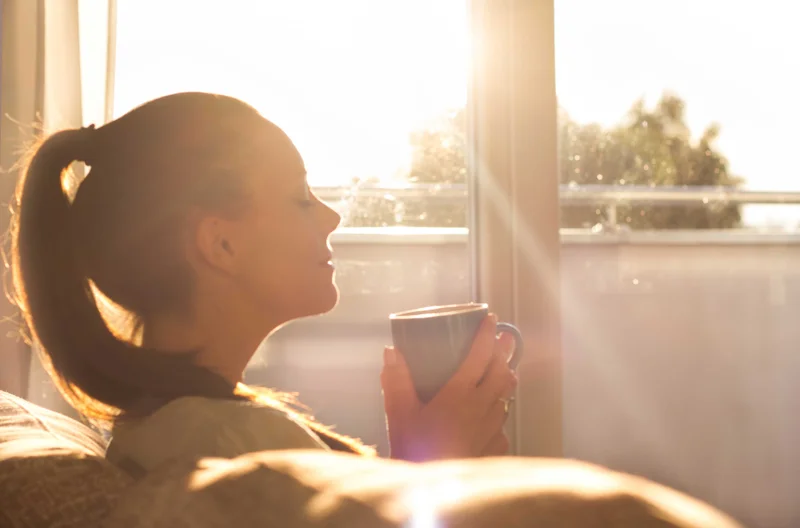 Woman relaxing on a lounge chair in a sunlit room.