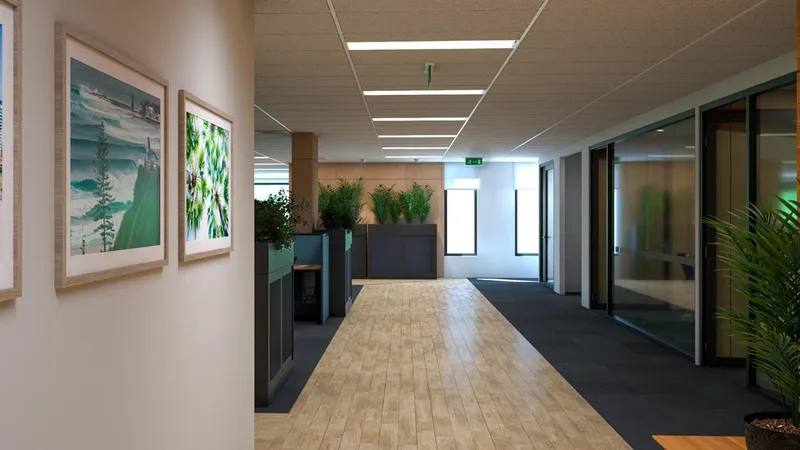 Office corridor with timber flooring, framed coastal artwork, and glazed meeting rooms at QBuild's South Coast Offices.
