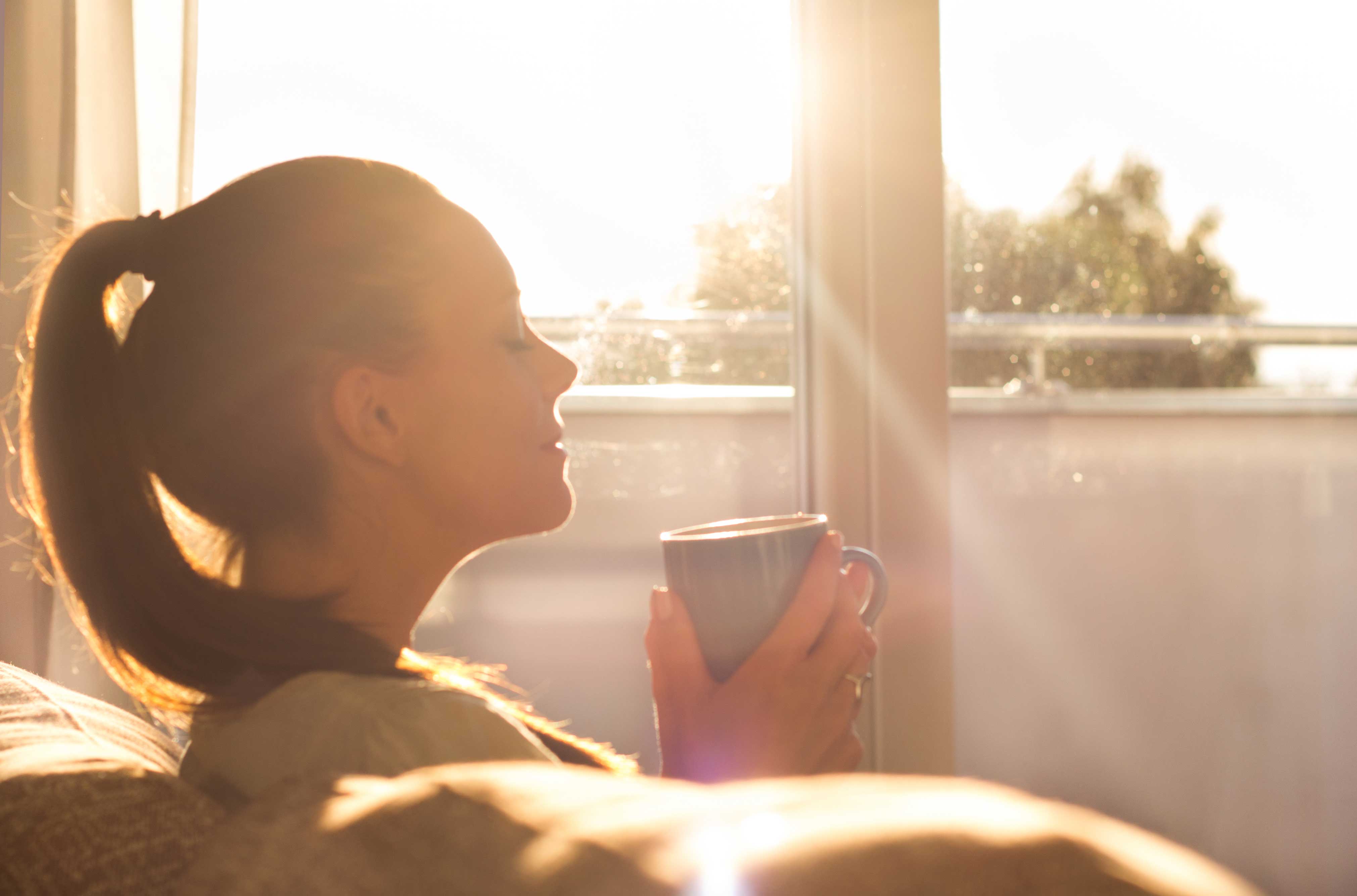 Woman relaxing on a lounge chair in a sunlit room.